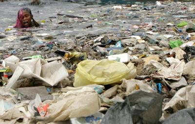 Boy swimming in a sea of plastics. Manila Bay.